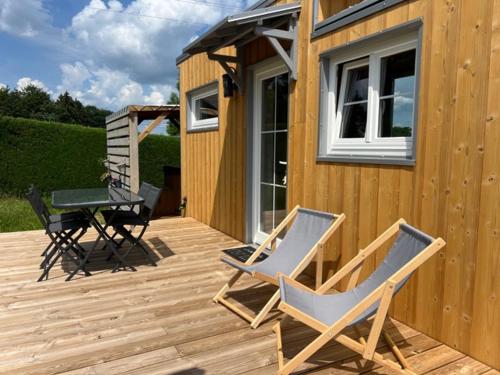 une terrasse avec une table et des chaises ainsi qu'une maison dans l'établissement La Tiny House, La Chandeleytte, à Champdray