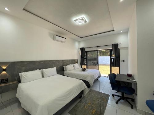 a bedroom with two beds and a desk and a window at Rabi’s guesthouse in Mahikeng