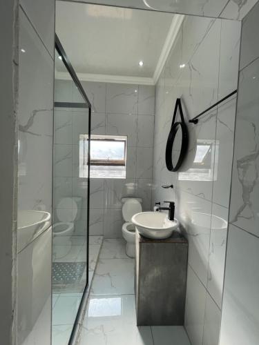 a white bathroom with a sink and a toilet at Rabi’s guesthouse in Mahikeng