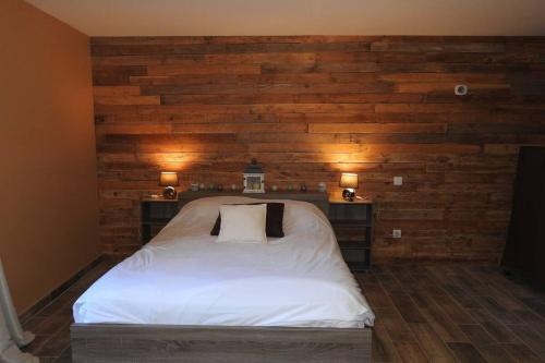 - une chambre avec un lit blanc et un mur en bois dans l'établissement Magnifique corp de ferme rénové, à Changey