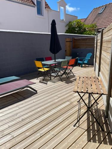 une terrasse avec des chaises, une table et un parasol dans l'établissement Wissant Maison Chez Jeanne, à Wissant