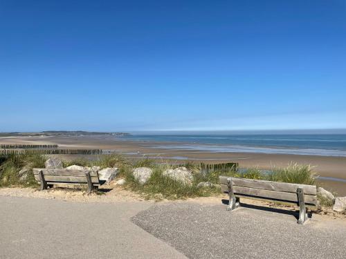 deux bancs assis sur une plage près de l'océan dans l'établissement Wissant Maison Chez Jeanne, à Wissant