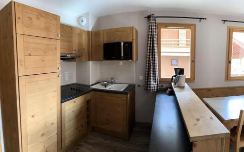 une cuisine avec des armoires en bois et un comptoir dans l'établissement Chalet Des Rennes - Super duplex résidence de standing au pied des pistes MAE-9741, à Vars