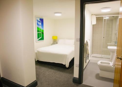 a bedroom with a bed and a bathroom with a sink at The George Wright Boutique Hotel, Bar & Restaurant in Rotherham