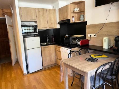 une cuisine avec une table et un réfrigérateur blanc dans l'établissement Résidence Gaubert - Studio cabine à Vars pour 4 personnes idéalement situé MAE-9831, à Vars