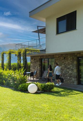 two people walking outside a house with a frisbee on the grass at Gazzi Apartments 'Panoramic & Relaxing' in Arco