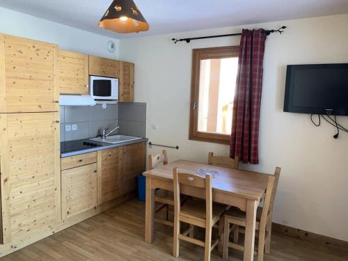 - une cuisine avec une table en bois, un évier, une table et des chaises dans l'établissement Chalet Des Rennes - Appart tout confort plein sud dans résidence de standing & garage au pied des pistes MAE-0001, à Vars