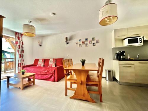 a living room with a table and a red couch at Résidence Pra Sainte Marie - T2 de standing avec piscine au pied du télésiège Sainte Marie MAE-0051 in Vars