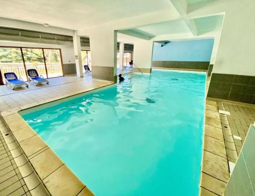 a swimming pool with blue water in a building at Résidence Pra Sainte Marie - T2 de standing avec piscine au pied du télésiège Sainte Marie MAE-0051 in Vars