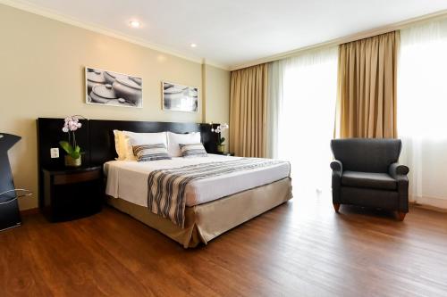 a bedroom with a large bed and a chair at Bourbon Residence Barra da Tijuca - Rio de Janeiro in Rio de Janeiro