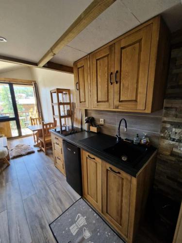 - une cuisine avec des placards en bois et un évier noir dans l'établissement Résidence Grizzli - Magnifique T2 6 couchages au centre de VARS MAE-0121, à Vars