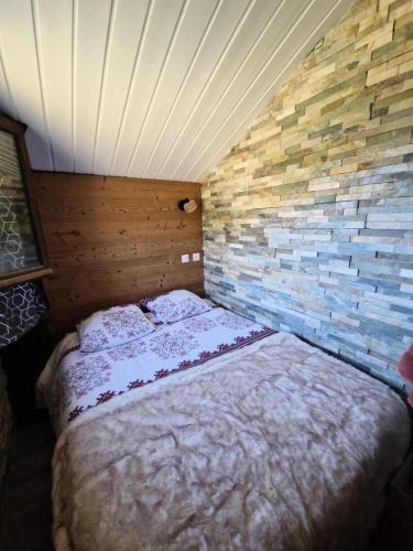 un lit dans une chambre avec un mur de briques dans l'établissement Résidence Grizzli - Magnifique T2 6 couchages au centre de VARS MAE-0121, à Vars