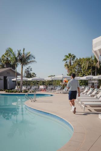 a man walks by a swimming pool at a resort at The Langham Huntington, Pasadena in Pasadena