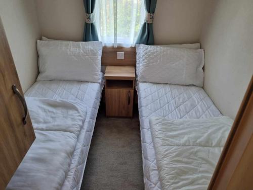 a small room with two beds and a desk at Pg115 GOLDEN PALM CHAPEL ST LEONARDS in Chapel Saint Leonards
