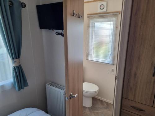 a small bathroom with a toilet and a window at Pg115 GOLDEN PALM CHAPEL ST LEONARDS in Chapel Saint Leonards