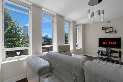 a living room with a couch and a tv and windows at 1560 sqft Elegant Condo at Downtown Hi-End Shopping & Dining Area - CN Tower View, Bidet, LockBox in Toronto