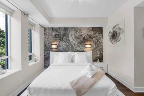 a bedroom with a white bed and a wall at 1560 sqft Elegant Condo at Downtown Hi-End Shopping & Dining Area - CN Tower View, Bidet, LockBox in Toronto