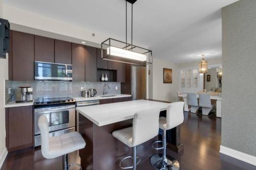 a kitchen with a island with white bar stools at 1560 sqft Elegant Condo at Downtown Hi-End Shopping & Dining Area - CN Tower View, Bidet, LockBox in Toronto