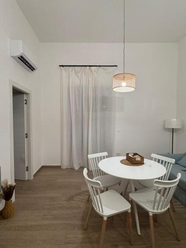 a white dining room with a white table and chairs at Maison Comì in Frattamaggiore