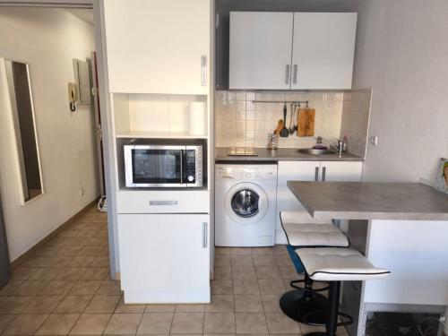 une cuisine avec des armoires blanches et une laveuse et une sécheuse dans l'établissement Studio SETE CV, à Sète
