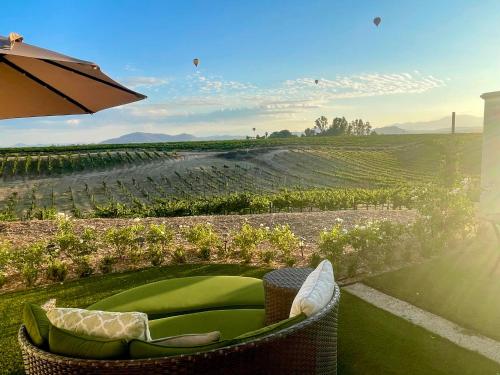a chair and an umbrella in front of a vineyard at Domaine Chardonnay in Temecula