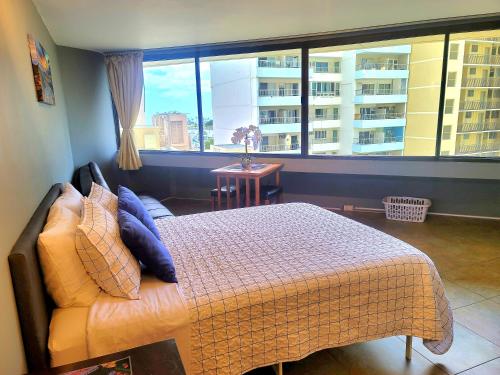 a bedroom with a bed and a large window at Waikiki Studio Steps to Beach-Mall Free Parking-WiFi in Honolulu