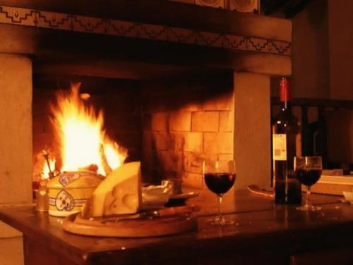 a fireplace with a plate of food and two glasses of wine at Casa colonial em Itù - Sorocaba in Mairinque