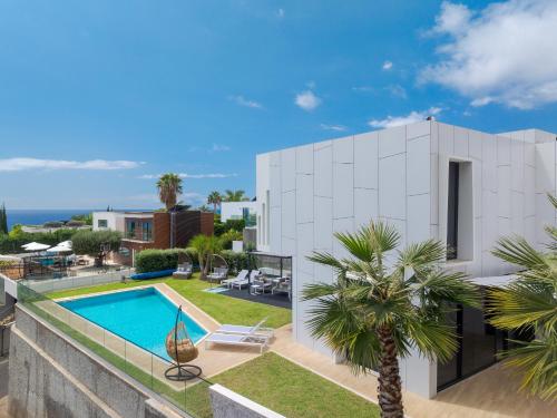 a white house with a swimming pool and palm trees at Luxury Diamond House by Holiday Rental Madeira in Funchal