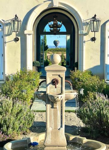a stone fountain in front of a building with an arch at Domaine Chardonnay in Temecula