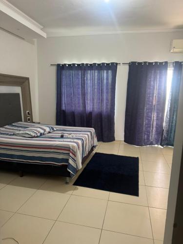 a bedroom with two beds and purple curtains at Hospedaria Mantovani in Tatuí