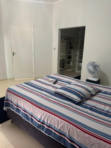 a bed with a striped blanket in a bedroom at Hospedaria Mantovani in Tatuí