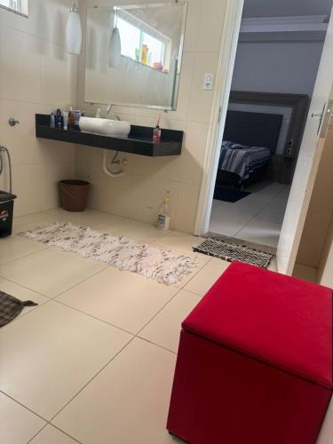 a bathroom with a sink and a red ottoman at Hospedaria Mantovani in Tatuí