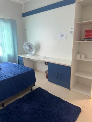 a bedroom with a bed and a desk with a fan at Hospedaria Mantovani in Tatuí