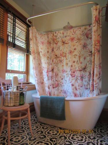 a bathroom with a bath tub with a floral shower curtain at Hummingbird Gardens B&B in Ladysmith