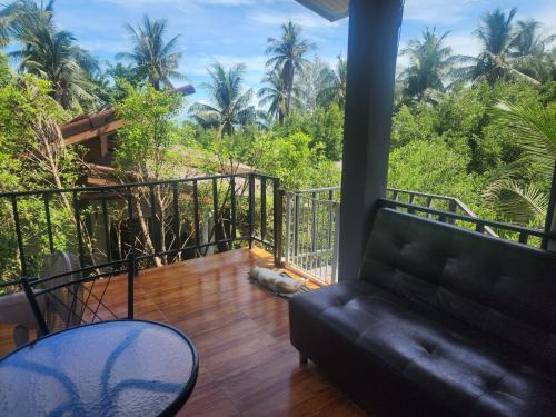 a living room with a couch and a balcony with trees at Mangrove beach house Sri Thanu in Srithanu