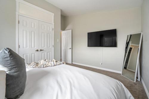 a bedroom with a white bed and a flat screen tv at Timber Valley I HotTub I PingPong I Sleep 14 I BBQ in Drumheller