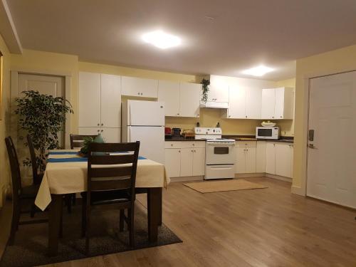 a kitchen with white cabinets and a table with chairs at Angela's Private Suites in Surrey