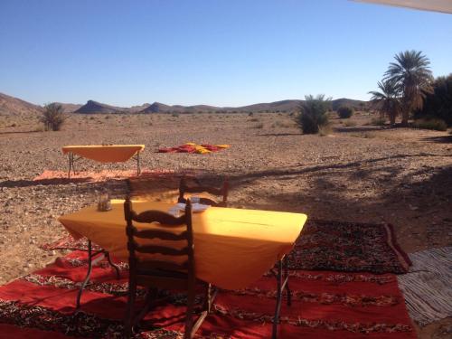 a table and chairs in the middle of the desert at Maison Boutchrafine in Erfoud