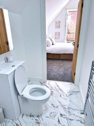 a white bathroom with a toilet and a bedroom at The Luxe Haven Penthouse - Sleeps 4 Apartment Nottingham City Centre in Nottingham