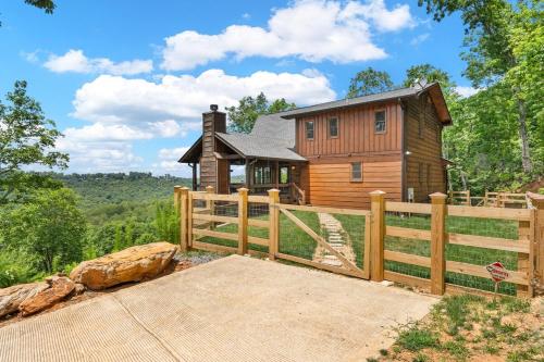 ein Holzhaus mit einem Zaun davor in der Unterkunft Luxury 4Br Game Room Hot tub long-range Mtn view in Blue Ridge
