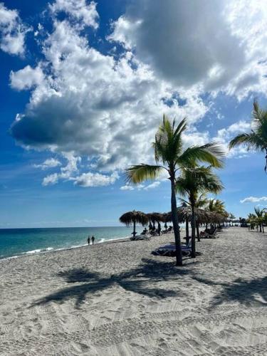 a sandy beach with palm trees and the ocean at Ocean 3 Condo By Abitre Playa Blanca in Río Hato