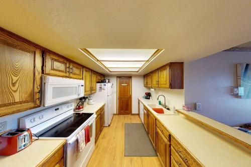 a large kitchen with wooden cabinets and white appliances at Royal Vista II Pool-Spa Ski-in out Gym, Sauna, Laundry, BBQ in Brian Head