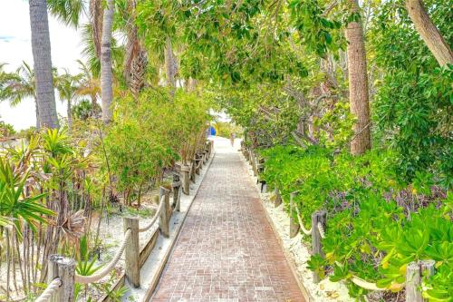 a brick path through a garden with palm trees at New! Remodeled, Pool-Side, 1-min to Beach Path! in Siesta Key