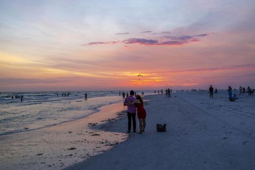 a group of people standing on the beach at sunset at New! Remodeled, Pool-Side, 1-min to Beach Path! in Siesta Key
