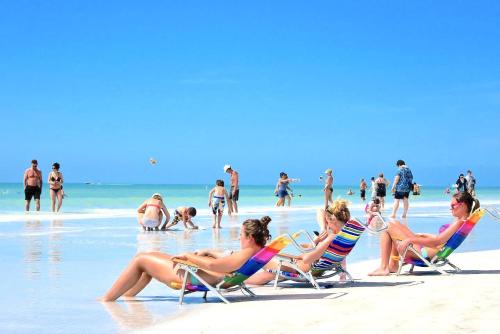 a group of people sitting in lawn chairs on the beach at New Listing! Pool Jacuzzi, 3-min to Beach Bars & Entertainment! in Siesta Key