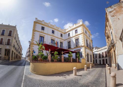 a white building with a red awning on a street at Hotel Palacio de Hemingway in Ronda