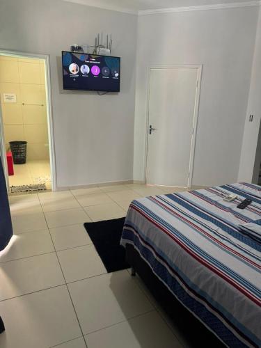 a bedroom with a bed and a tv on the wall at Hospedaria Mantovani in Tatuí