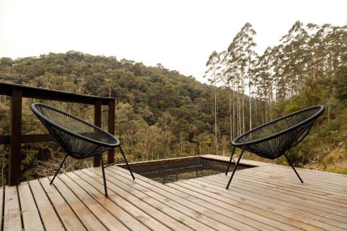 two chairs sitting on top of a wooden deck at Chalé Alcântara - Com banheira para casal in São Pedro de Alcântara
