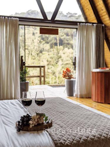 two glasses of wine sitting on a bed in a room at Chalé Alcântara - Com banheira para casal in São Pedro de Alcântara