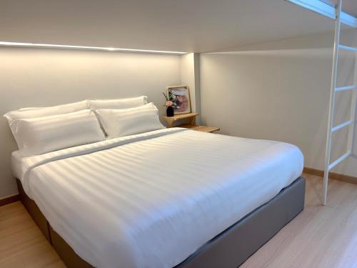 a large bed with white sheets and pillows in a room at La Vie Hotel Juru in Simpang Ampat